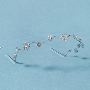 Détail d'un serre-tête argenté avec flocons de neige et strass sur fond bleu clair