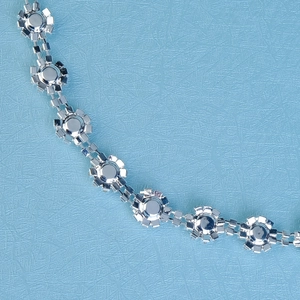 Détail d'une ceinture chaîne argentée à motif de tournesol ornée de strass brillants