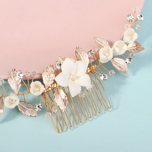 Dettaglio del pettine per capelli sposa con foglie dorate e fiori in ceramica bianca