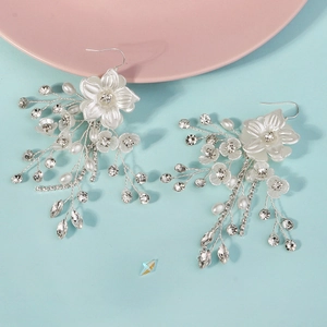 Boucles d'oreilles fleurs en perles blanches pour mariée sur un fond bleu azur vif