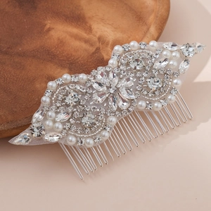 Elegant bridal hair comb with white pearls and sparkling rhinestones on a wooden tray