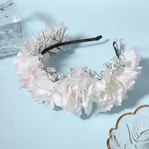 Elegant bridal floral headband with white silk roses and crystal beads on a blue background