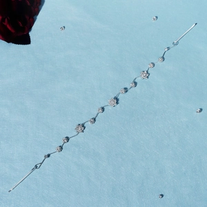 Détail d'un bandeau de mariée argenté avec des flocons de neige en strass sur fond bleu clair