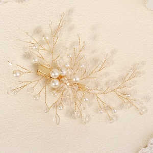 Detailed macro view of handmade bridal hair clip with gold wires, pearls and crystals