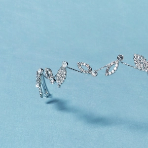 Gros plan détaillé d'un bandeau de mariée argenté avec des motifs de feuilles en cristal
