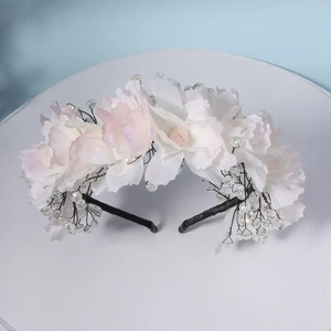 Close-up of white silk fabric flowers and crystal beads on a handmade bridal headband