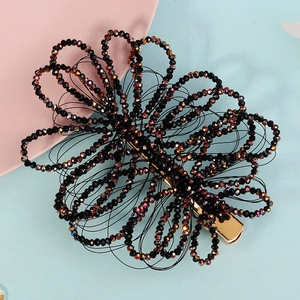 Detailed view of handmade black beaded floral hair clip with iridescent faceted beads