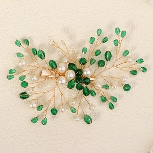 Detail of bridal hair clip with green crystals, white pearls and gold wire branches