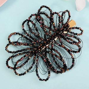Close-up of handmade black iridescent crystal beads on a golden duckbill hair clip