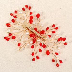 Detail of handmade bridal hair clip with red crystals, pearls, and gold wire floral branch