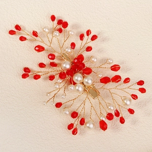Detailed view of handmade bridal hair clip with red crystals and white pearls on gold wire