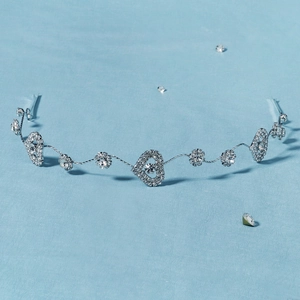 Détail d'un serre-tête de mariée argenté avec cristaux de cœur et fleurs sur fond bleu