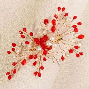 Detail of bridal hair clip with red crystals and cream pearls on gold wire branches