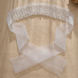 Close-up of elegant bridal sash with white pearls on translucent organza ribbon detail