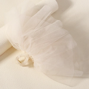 Close-up of elegant white multilayered tulle bow bridal hair clip with resin claw
