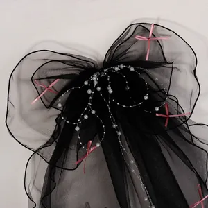 Detail of black mesh hair bow with white pearls and pink satin ribbon accents