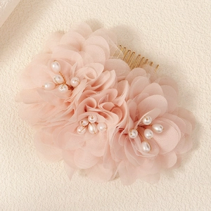 Detail of pink mesh flowers with white faux pearl centers on a gold metal bridal hair comb