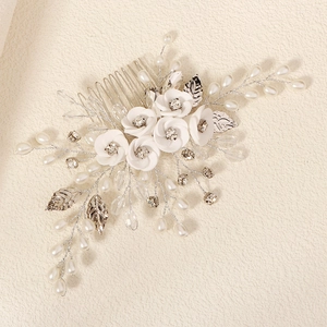 Detailed macro view of white clay flowers and shiny rhinestones on a bridal hair comb