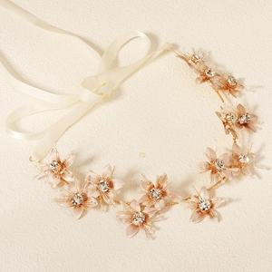 Détail d'un bandeau de mariée en métal doré avec fleurs en cristal et rubans de satin