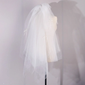 Detail view of multi-layer white bridal veil with satin ribbon bows and hair clip