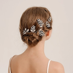 Detail of silver floral hair vine with metal petals and dark center on a braided hairstyle