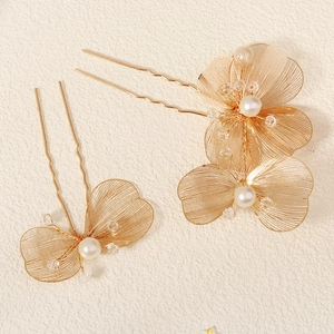 Dettaglio di petali in filo dorato fatti a mano con perle su forcine da sposa