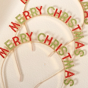 Detailed close-up of golden metal Merry Christmas headband with red and green rhinestones