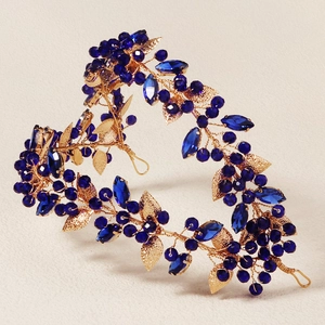 Detailed close-up of golden wire headband with blue marquise crystals and metallic leaves