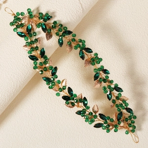 Detail of handcrafted gold wire bridal headpiece with green crystals and golden leaves