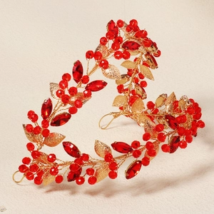 Close-up of handmade bridal headband featuring red crystals and golden filigree leaves