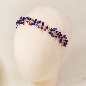 Détail du bandeau en cristal bleu marine avec feuilles dorées sur un modèle de tête en tissu