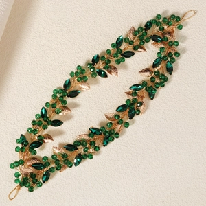 Elegant gold bridal headband with green crystals and leaf motifs for wedding hair styling