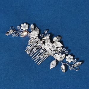 Détail d'un peigne de mariée avec fleurs en cristal et perles blanches sur fond bleu