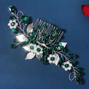 Vue détaillée d'un peigne à cheveux de mariée avec cristaux verts, perles et feuilles