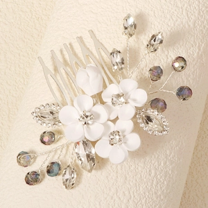 Close-up of handmade bridal hair comb with white polymer clay flowers and sparkling crystals