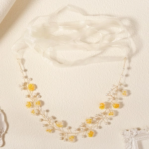 Detail of yellow flowers and white pearls on golden wire bridal headband with organza ribbons