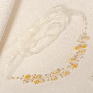Detail of handmade bridal headband with yellow flowers, white pearls and organza ribbons
