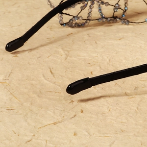 Detailed close-up of beaded mesh structure and smooth end protector on a black headband
