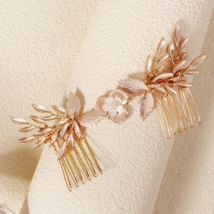 Elegant gold bridal hair comb set with white flowers and pearls on textured backdrop