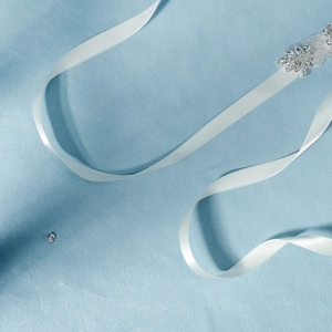 Détail de la ceinture de mariée en satin blanc avec des cristaux en forme de feuilles
