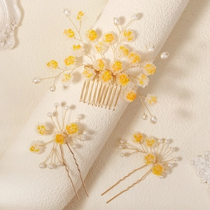 Détail d'un peigne et d'épingles à fleurs jaunes faits main avec fils dorés