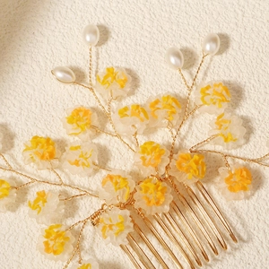 Détail de fleurs en résine jaune et de perles sur un peigne de mariée doré fait main