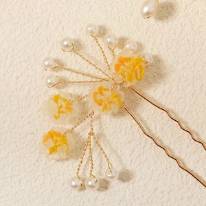 Détail d'épingle à cheveux de mariée avec fil doré et pétales de fleurs en résine jaune