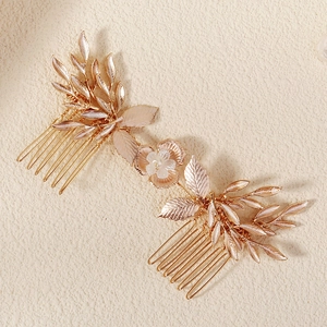 Detail showing two golden floral hair combs with leaf patterns and white beads for weddings