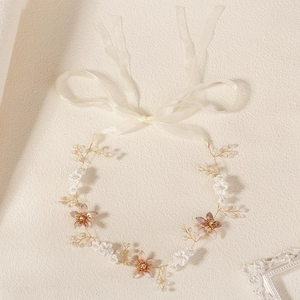 Détail du bandeau de mariée avec fils dorés, fleurs blanches et rubans en mousseline