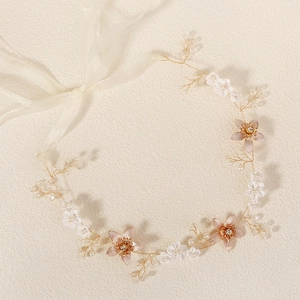 Détail d'un bandeau de mariée avec fleurs blanches, fil doré, perles et rubans de soie