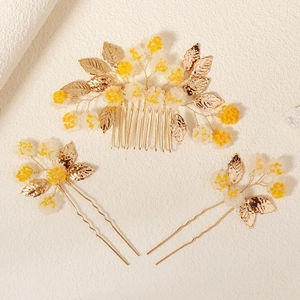 Détail de parure de mariée avec fil doré, fleurs jaunes et feuilles en métal