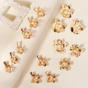 Détails de barrettes fleurs en métal doré ornées de perles blanches et textures fines