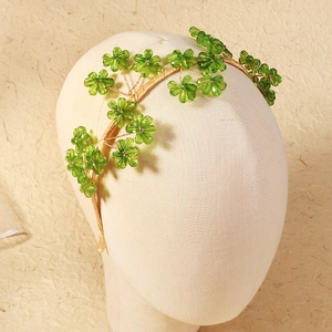 Detail of handmade beaded bridal headband with green crystal flowers on beige satin base