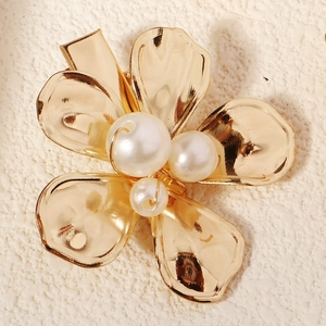Détail d'une pince à cheveux fleur en métal doré avec pétales martelés et perles